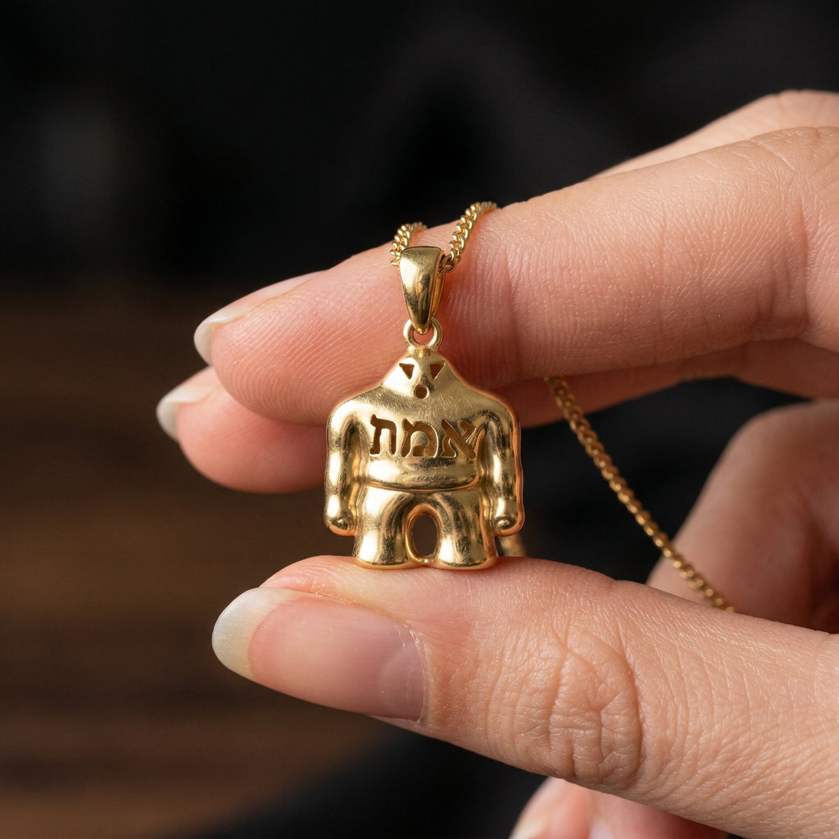 Gold-plated silver Golem pendant held between two fingers